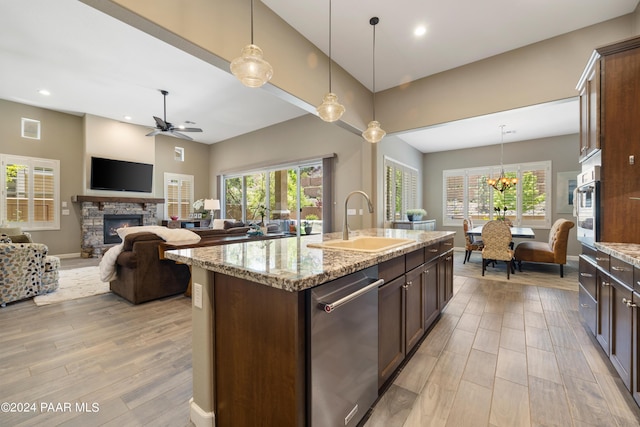 kitchen featuring a fireplace, decorative light fixtures, a kitchen island with sink, and sink