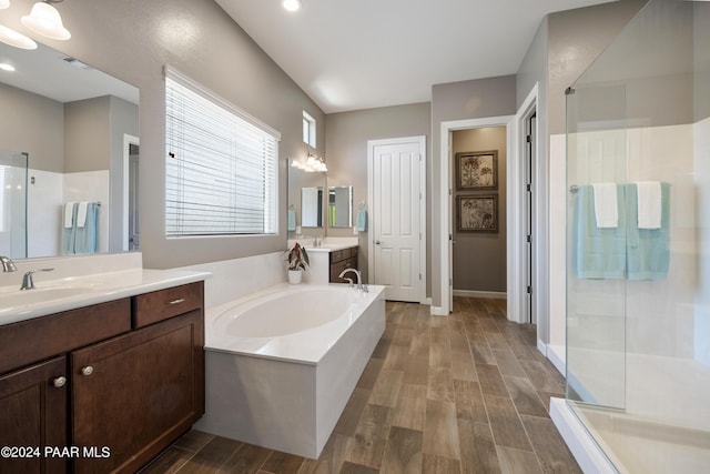 bathroom with wood-type flooring, vanity, and shower with separate bathtub