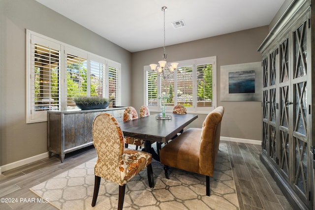 dining room featuring wood-type flooring, a wealth of natural light, and a notable chandelier