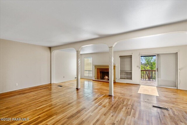 2403 Country Park Dr, Prescott, AZ 86305 - unfurnished living room featuring arched walkways, wood finished floors, a fireplace, and decorative columns