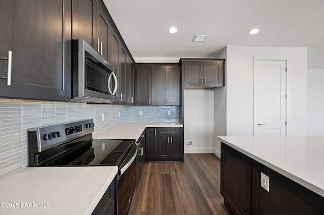 kitchen with appliances with stainless steel finishes, dark hardwood / wood-style floors, backsplash, and dark brown cabinets