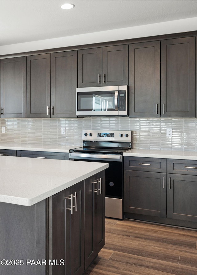 kitchen featuring dark brown cabinets, dark wood-type flooring, stainless steel appliances, and decorative backsplash