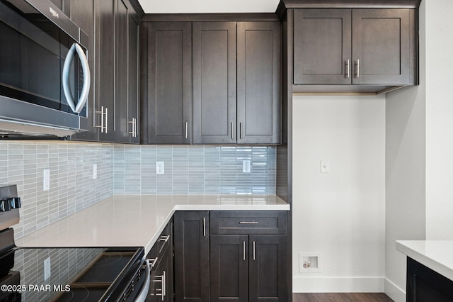 kitchen featuring backsplash, dark brown cabinetry, wood-type flooring, and range with electric stovetop