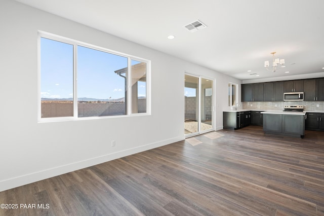 kitchen with dark wood-type flooring, plenty of natural light, a chandelier, and backsplash