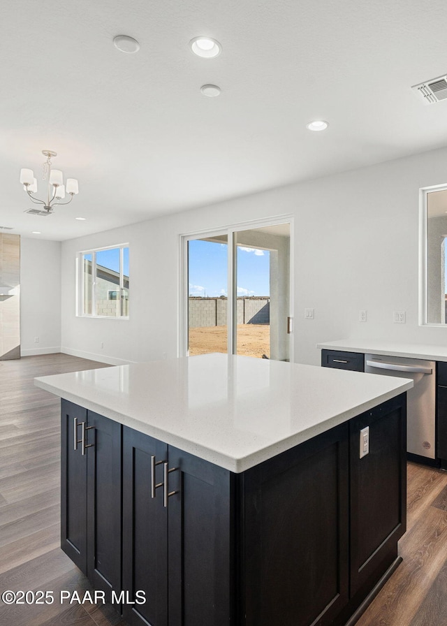 kitchen featuring a kitchen island, dark hardwood / wood-style floors, decorative light fixtures, dishwasher, and an inviting chandelier