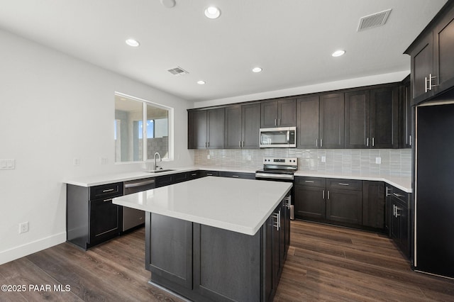 kitchen with a kitchen island, appliances with stainless steel finishes, sink, dark hardwood / wood-style flooring, and dark brown cabinetry