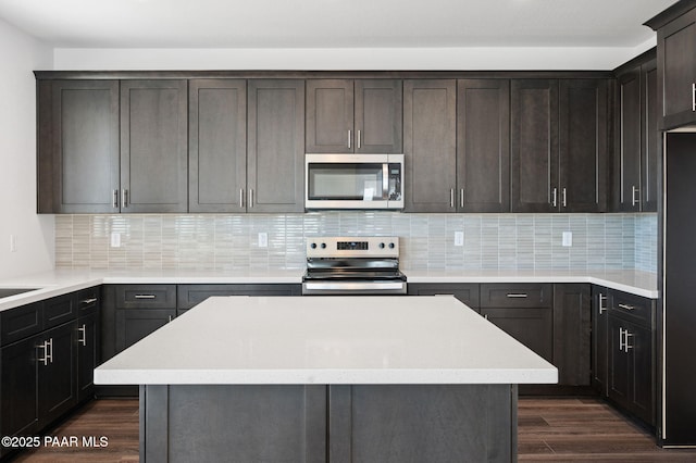 kitchen featuring dark hardwood / wood-style flooring, decorative backsplash, stainless steel appliances, and a center island