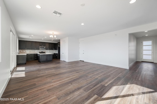 unfurnished living room featuring a notable chandelier and dark hardwood / wood-style floors