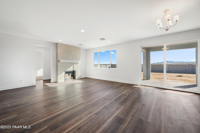 unfurnished living room with a notable chandelier, dark wood-type flooring, a tile fireplace, and a mountain view