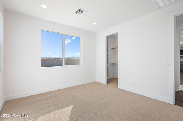 unfurnished bedroom with a spacious closet, light colored carpet, and a closet