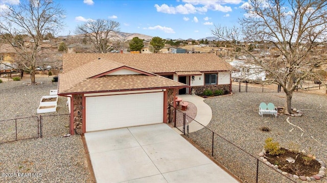 single story home with a mountain view, a garage, a shingled roof, fence, and concrete driveway