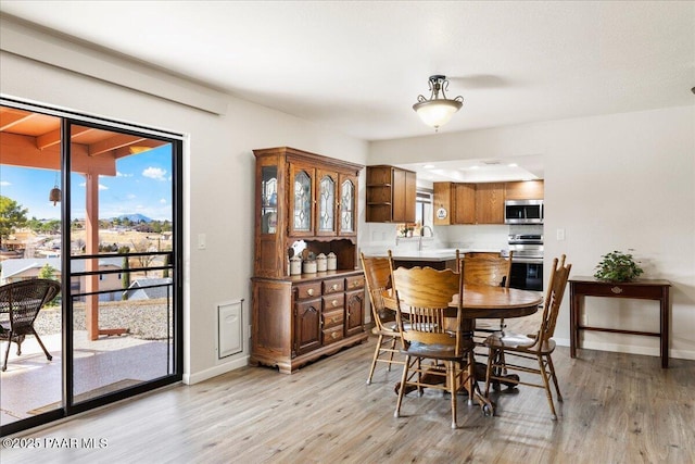 dining space featuring baseboards and light wood-style floors