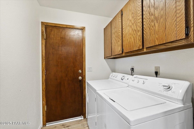 laundry room featuring cabinet space, light wood-style flooring, and washer and dryer