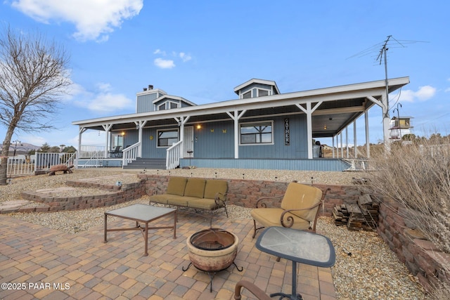 view of patio featuring a porch and an outdoor living space with a fire pit