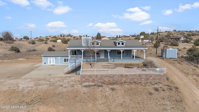 view of front of home featuring a porch and a storage shed