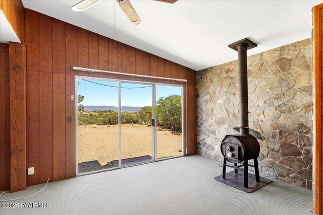 1485 S Pima Rd, Dewey-Humboldt, AZ 86327 - unfurnished living room featuring lofted ceiling, carpet flooring, a wood stove, wood walls, and ceiling fan