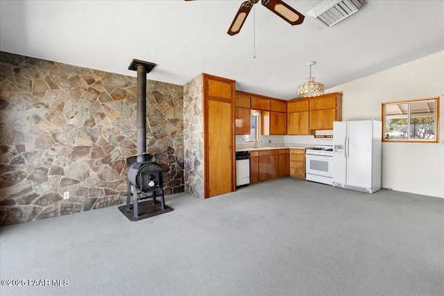 1485 S Pima Rd, Dewey-Humboldt, AZ 86327 - kitchen with white appliances, a ceiling fan, light colored carpet, brown cabinetry, and a wood stove