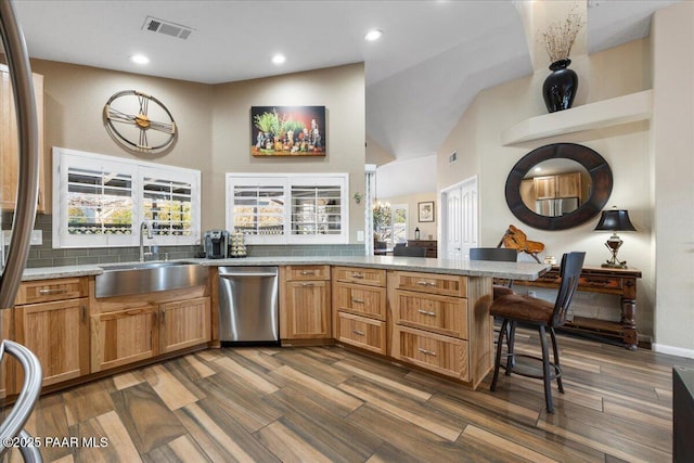 kitchen featuring a kitchen bar, kitchen peninsula, backsplash, sink, and dishwasher