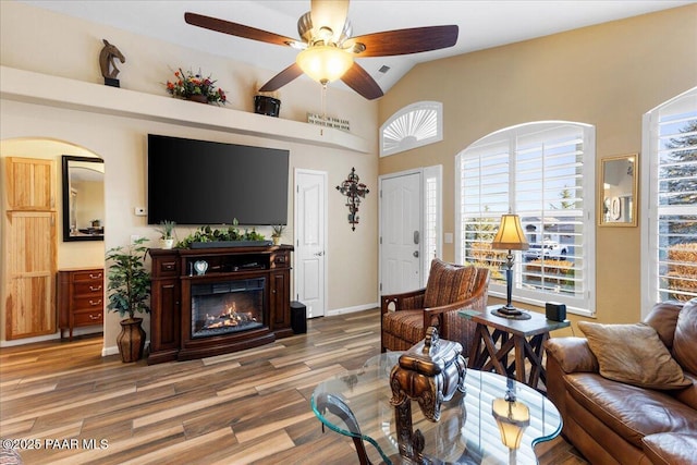 living room with hardwood / wood-style flooring, ceiling fan, and vaulted ceiling