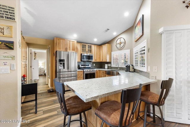 kitchen featuring kitchen peninsula, tasteful backsplash, stainless steel appliances, sink, and hardwood / wood-style flooring