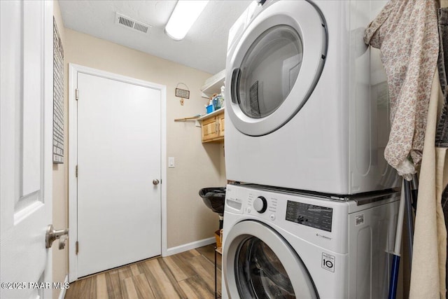 washroom featuring light hardwood / wood-style flooring and stacked washer and clothes dryer