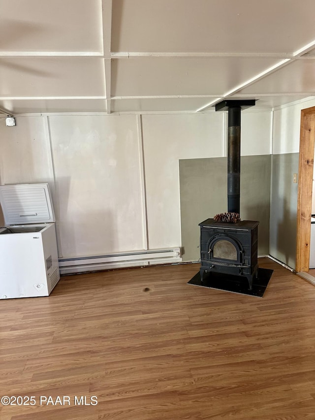 details with wood-type flooring, a baseboard radiator, and a wood stove