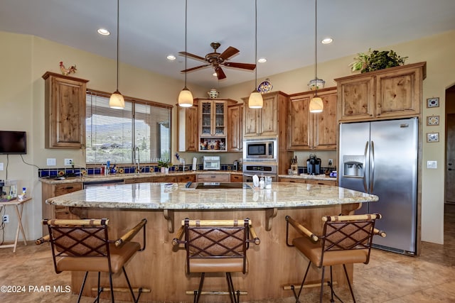kitchen featuring stainless steel appliances, a ceiling fan, brown cabinetry, light stone counters, and recessed lighting