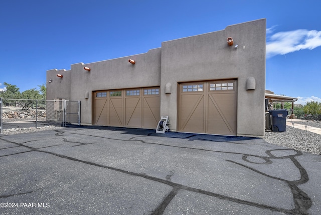 view of front of home featuring stucco siding, a garage, asphalt driveway, and a gate