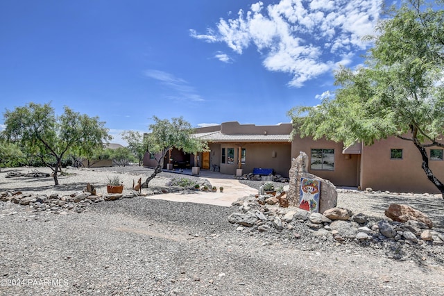 rear view of house with a tiled roof, a patio area, and stucco siding