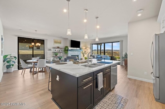 4947 Mclaury Dr, Prescott Valley, AZ 86314 - kitchen with appliances with stainless steel finishes, light wood-style floors, open floor plan, a kitchen island with sink, and pendant lighting