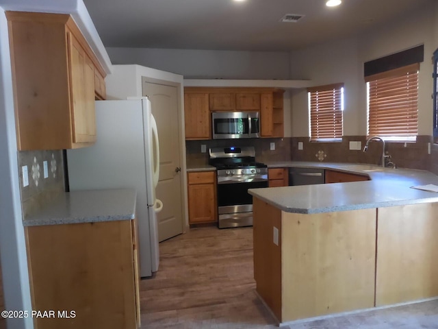 3575 N Meadowlark Dr, Prescott Valley, AZ 86314 - kitchen with stainless steel appliances, a peninsula, light countertops, tasteful backsplash, and light wood-style flooring