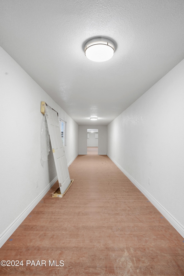 basement featuring light wood-type flooring and a textured ceiling