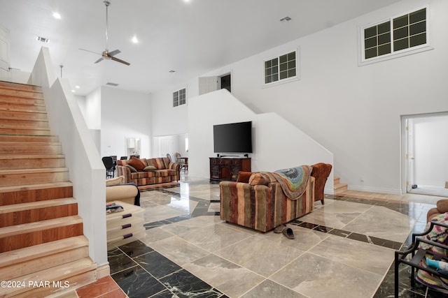 living room with ceiling fan and a high ceiling