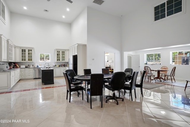 tiled dining room with ceiling fan and a towering ceiling