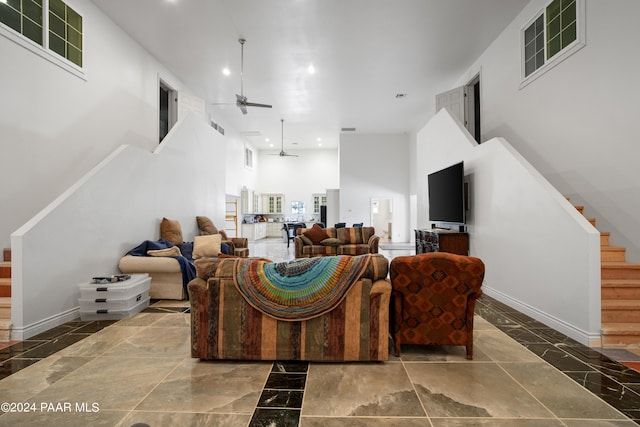 living room with ceiling fan and a towering ceiling