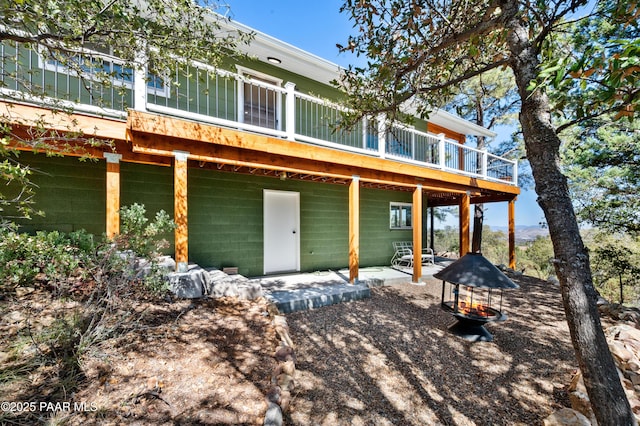 back of house featuring a wooden deck, a fire pit, and a patio area