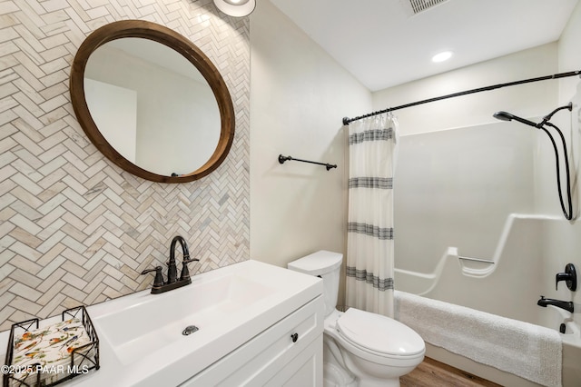 bathroom with decorative backsplash, toilet, vanity, and shower / bath combo