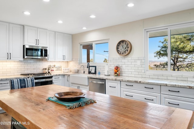 kitchen with stainless steel appliances, butcher block counters, and white cabinetry