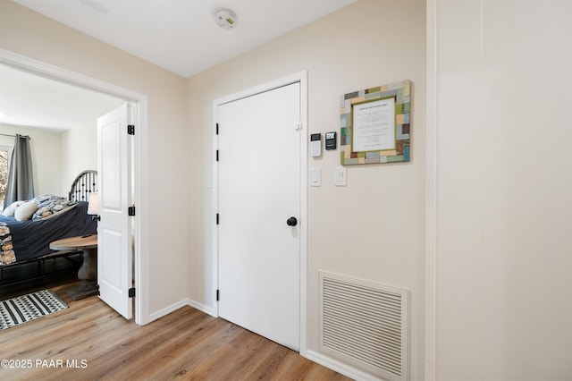 corridor featuring visible vents, light wood-style flooring, and baseboards