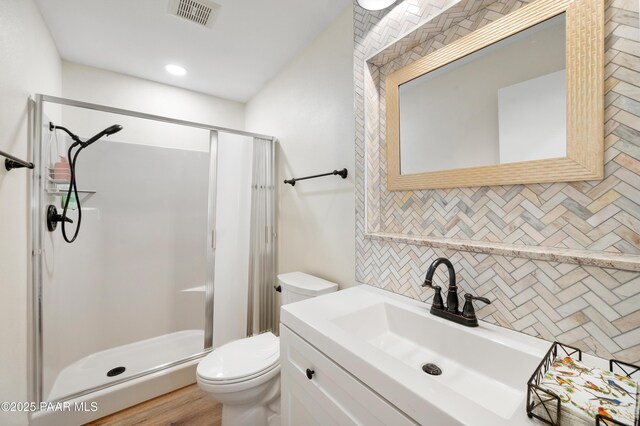 full bathroom featuring vanity, visible vents, a stall shower, decorative backsplash, and toilet