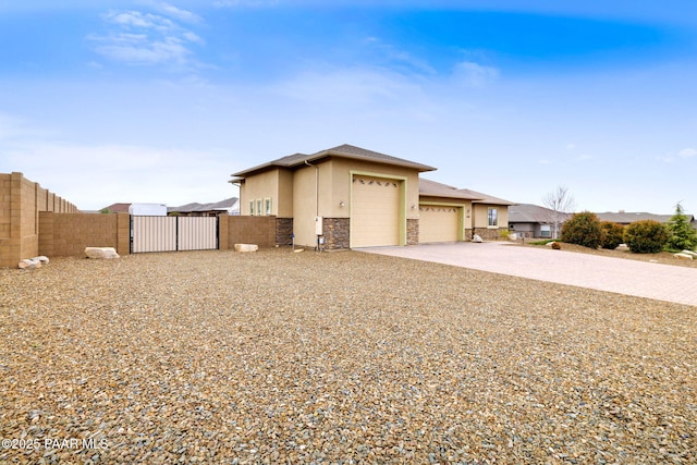 view of home's exterior with stucco siding, an attached garage, stone siding, driveway, and a gate