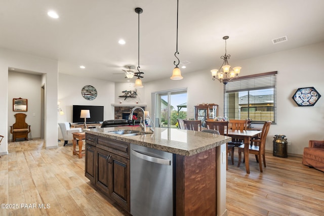 kitchen featuring a sink, a fireplace, dishwasher, open floor plan, and light wood-style flooring