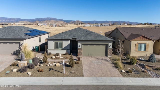 view of front of home with a mountain view, a garage, a shingled roof, decorative driveway, and stucco siding