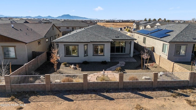 view of front of home featuring a fenced backyard, a residential view, a mountain view, and a shingled roof