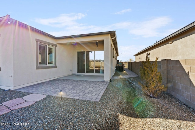 rear view of house with a patio, fence, and stucco siding