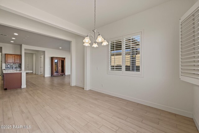 interior space featuring light wood finished floors, recessed lighting, baseboards, and an inviting chandelier