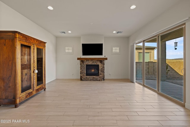 unfurnished living room with light wood-style floors, recessed lighting, visible vents, and a stone fireplace