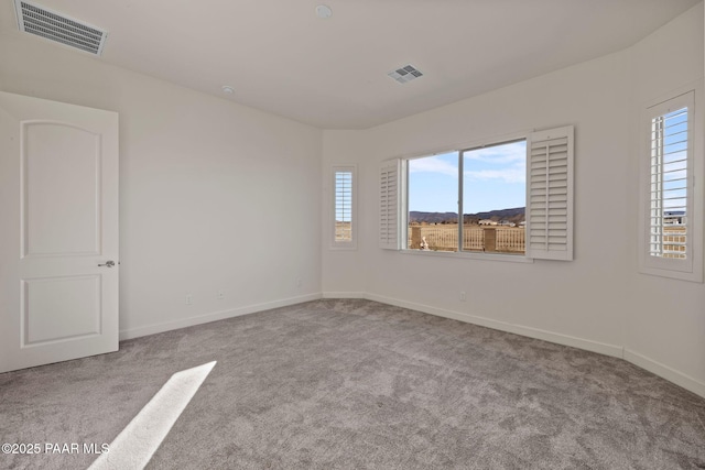 carpeted spare room featuring visible vents and baseboards