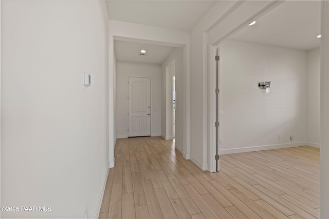 corridor with light wood-type flooring and baseboards