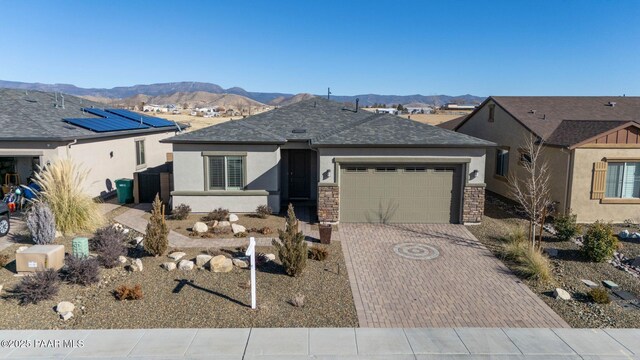 view of front of property featuring stone siding, decorative driveway, and stucco siding